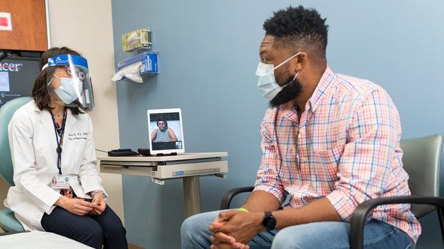 doctor speaking with young, African American colorectal cancer patient.