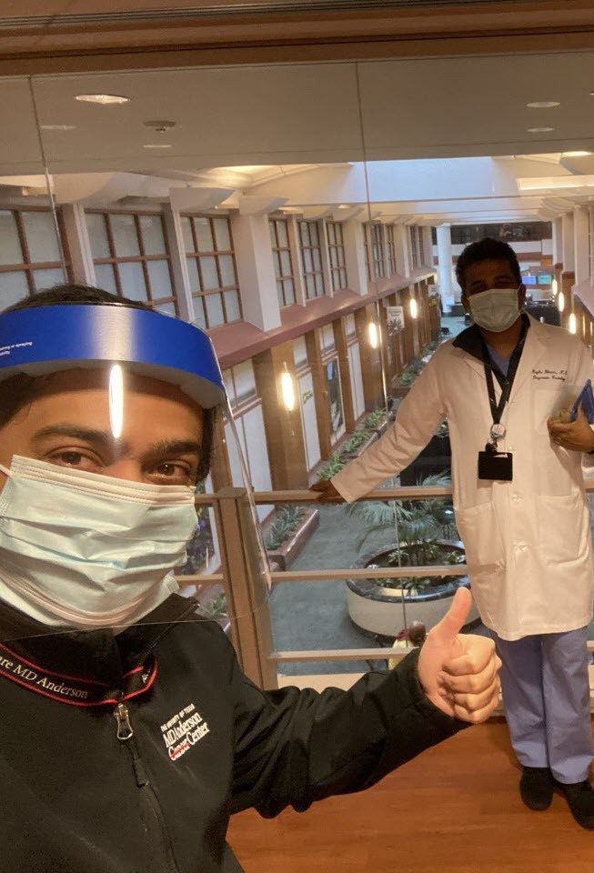 Three healthcare workers wearing masks make the thumbs-up sign