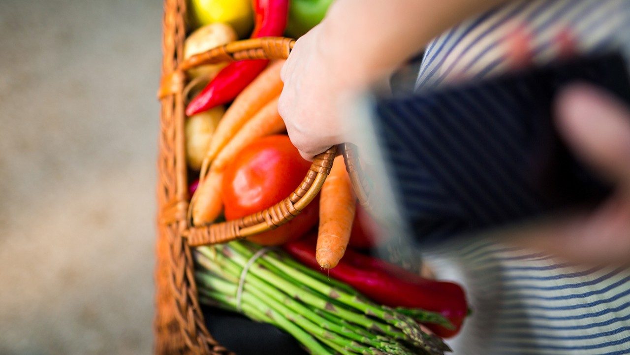 woman holding basket of vegetables